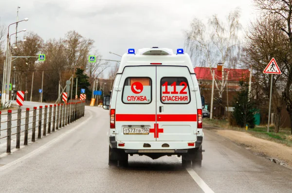 Moscú, Rusia - 19 de abril de 2020: pandemia mundial de coronavirus, coche de ambulancia ruso en movimiento en la carretera. Vista trasera. Inscripción en un coche, traducción: 112 Rescue Service — Foto de Stock