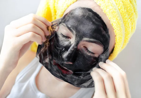 Nahaufnahme Porträt eines Teenie-Mädchens, das schwarze Gesichtshaut von der Maske entfernt. Wellness, Porenreinigung, Hautpflege, kosmetologische Behandlung zu Hause — Stockfoto