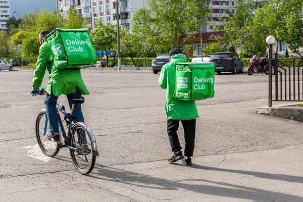 Moscú, Rusia-mayo de 2020: Dos mensajeros del club de reparto que llevan cajas verdes de entrega de alimentos con el logotipo de la empresa a pie y en bicicleta de McDonalds a los clientes. Empresa de entrega de comida rápida delivery — Foto de Stock
