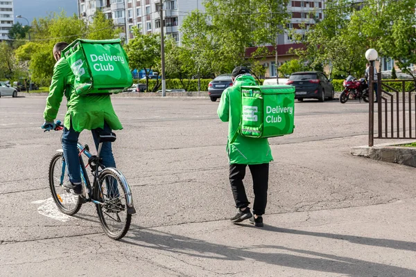 Moskova, Rusya-Mayıs 2020: Yiyecek taşıyan iki kurye şirket logosu taşıyan yeşil kutular ve McDonalds 'tan müşterilere bisikletle gidiyor. Fast food teslimatçısı.