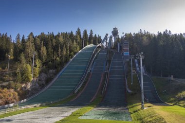 Three springboards and a tower with a viewing platform above the forest against a blue sky. Kuopio