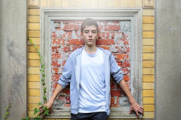 Beautiful teenage boy leaning against an old wall — Stock Photo, Image