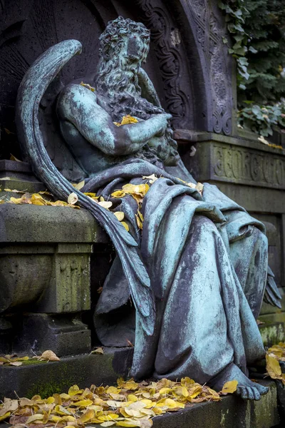 Скульптура старого выветрившегося архангела с осенними листьями . — стоковое фото