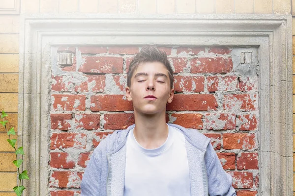 Portrait of a teenage boy leaning against a wall, with closed ey — Stock Photo, Image