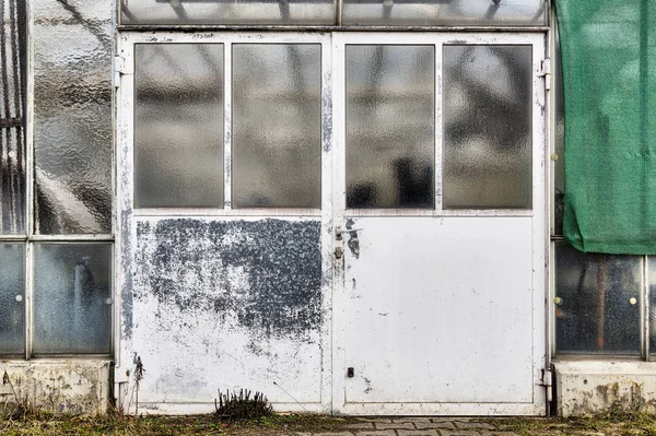 Old grungy metal door of a glass house — Stock Photo, Image