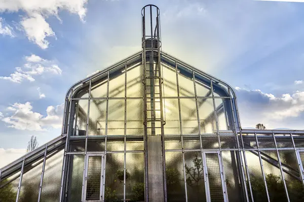 Glass house with the sun behind and dynamic sky — Stock Photo, Image