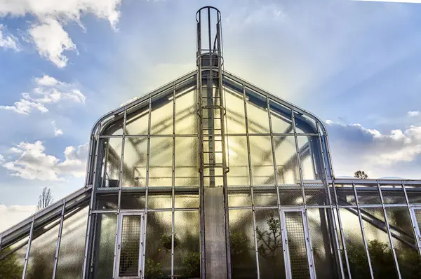 Casa de cristal con el sol detrás y el cielo dinámico —  Fotos de Stock