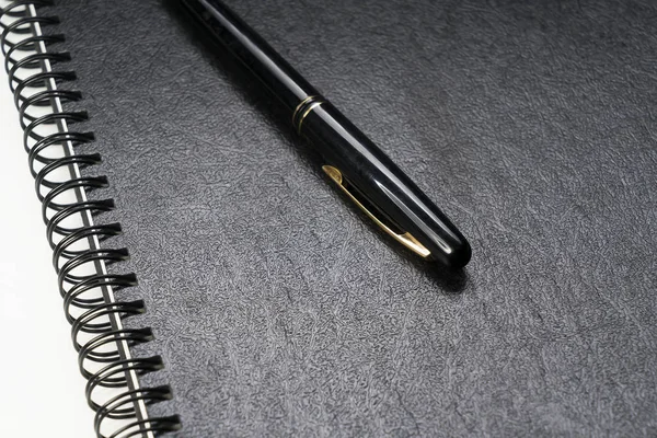 Black fountain pen laying on a black ring binder — Stock Photo, Image