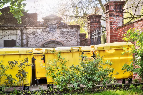 Benne à ordures jaune debout sur une cour intérieure — Photo