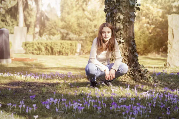 Молода жінка присідає на весняному квітковому лузі — стокове фото