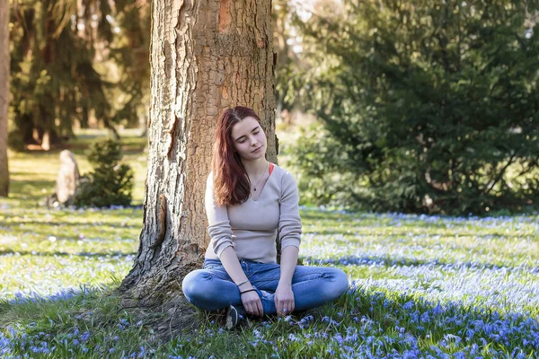 Jeune femme rêveuse assise dans un pré de fleurs — Photo