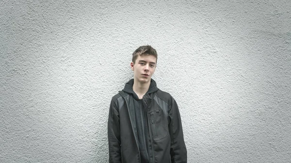 Portrait of a young man leaning against a white wall — Stock Photo, Image