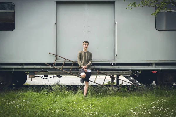 Young man leaning against an old rail car — Stock Photo, Image