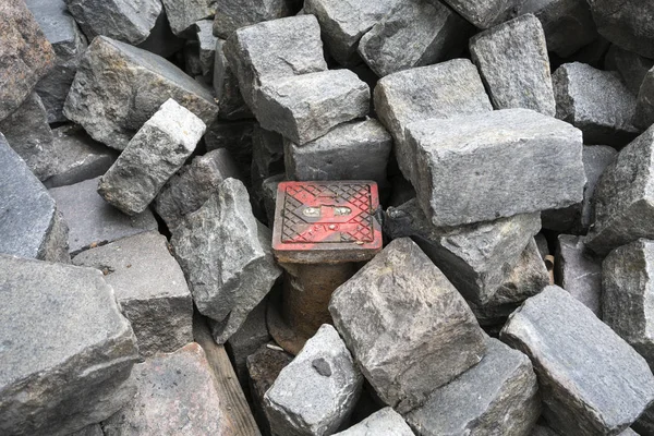 石畳の石の真ん中に小さな塗装下水道カバー — ストック写真