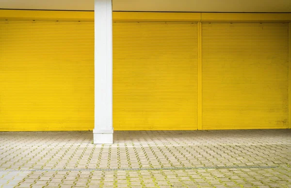 Yellow roller shutter and pavement for backgrounds and compositi — Stock Photo, Image