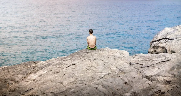Young man sitting on a cliff — Stock Photo, Image