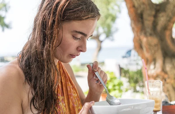 Mujer comiendo joven en un restaurante de playa — Foto de Stock