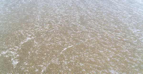 Schaum einer Welle am Strand für Hintergründe — Stockfoto