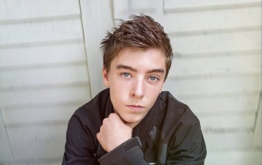 Bir kapının önünde oturan genç bir adam portresi