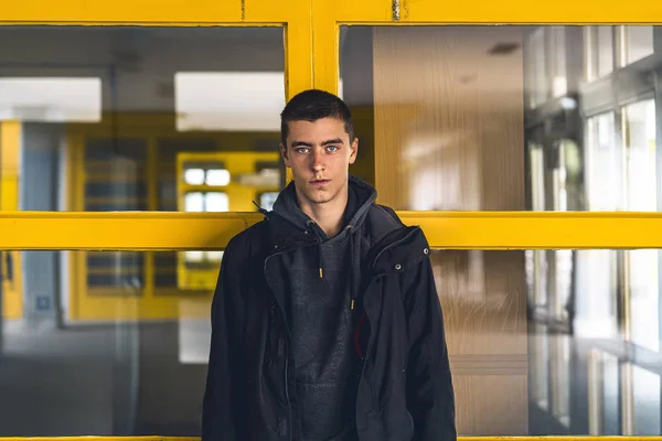 Portret van een lachende jongeman voor gele ramen — Stockfoto