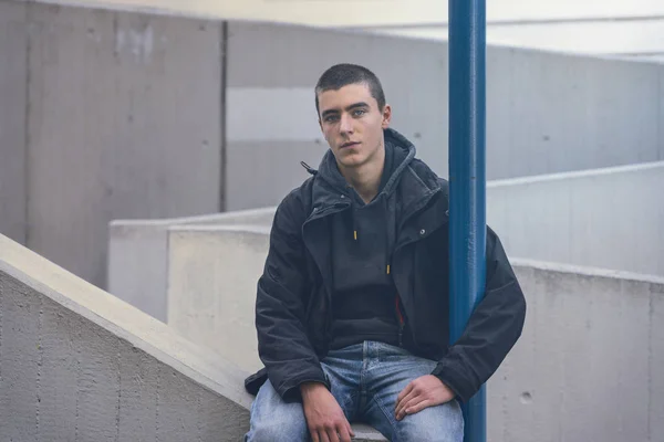 Portrait d'un jeune homme occasionnel assis sur un mur de béton — Photo