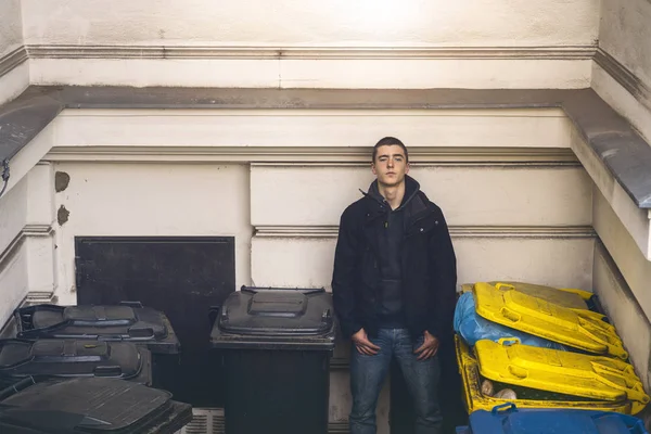 Портрет молодого человека, стоящего между мусорными баками — стоковое фото