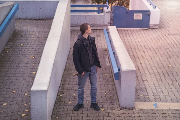 Jovem olhando ao redor entre paredes de concreto — Fotografia de Stock