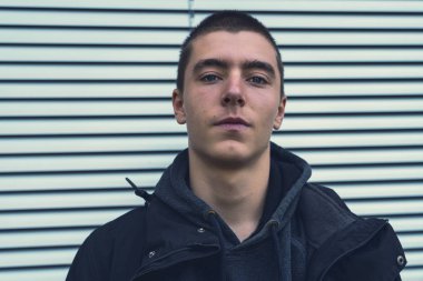 Paten kepenğinin önünde gülümseyen genç bir adamın portresi.