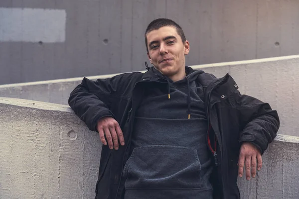 Portrait d'un jeune homme souriant appuyé contre un mur de béton — Photo