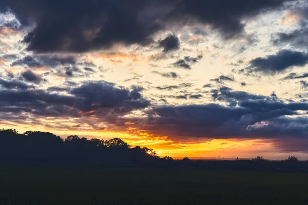 Beautiful sunset over a meadow with dramatic sky — Stock Photo, Image