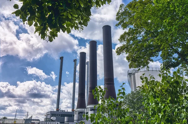 Tres grandes chimeneas de una central eléctrica con un hermoso cielo nublado Imágenes de stock libres de derechos