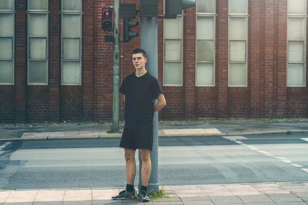 Portret van een eenzame jongeman die voor een rood verkeerslicht staat — Stockfoto