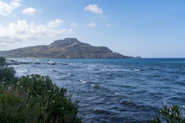 Girit 'te dağları ve mavi gökyüzü olan deniz manzarası