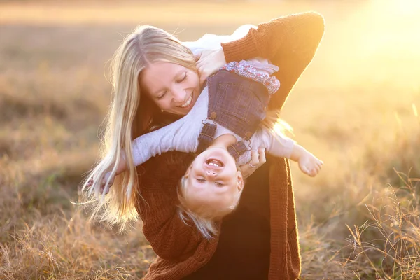 Gelukkig jonge moeder met Baby dochter buiten spelen bij zonsondergang — Stockfoto
