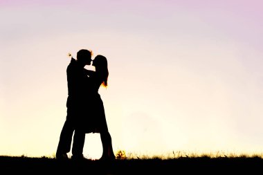 Genç bir çift dışında gün batımında sarılma sevgi dolu siluet