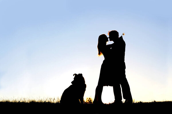 Silhouette of Loving Young Couple Hugging at Sunset Outside