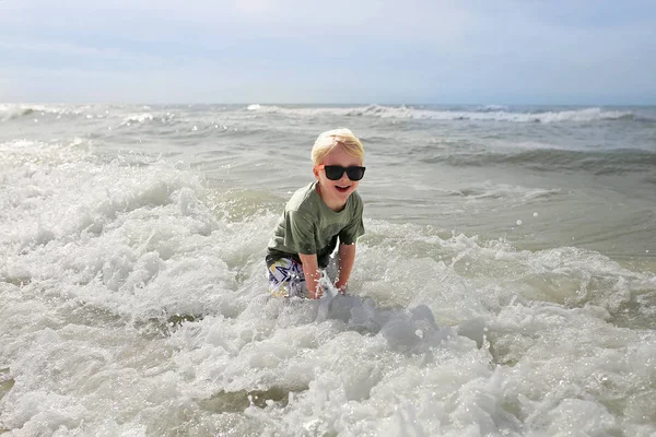 Enfant heureux jouant dehors dans les vagues de l'océan — Photo