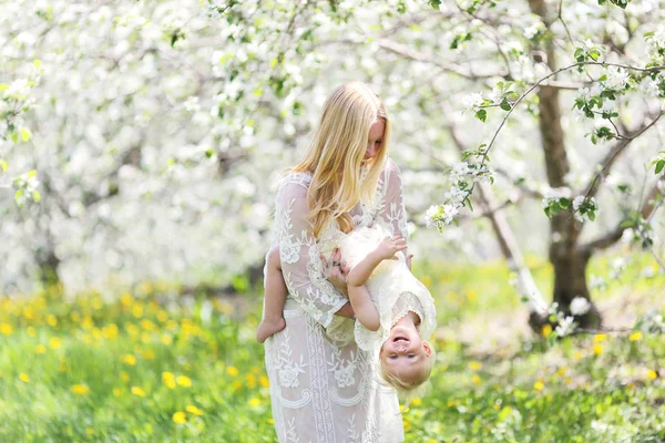 Šťastný matka tančí s dcerou v kvetoucí Apple Orcha — Stock fotografie