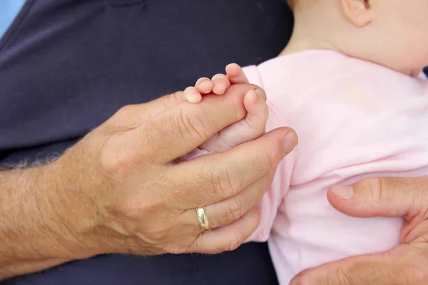 Большая рука человека, держащего крошечные пальчики маленькой девочки — стоковое фото