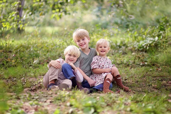 Familia de tres niños pequeños y felices posando afuera en el bosque —  Fotos de Stock