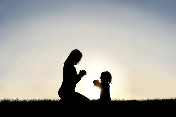 La jeune mère et son petit enfant prient dehors au coucher du soleil — Photo