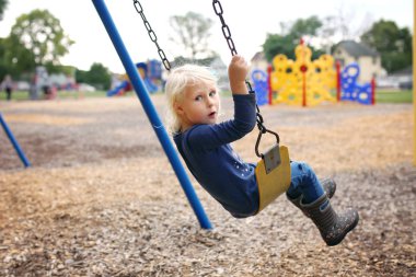 Sevimli küçük okul öncesi çocuk Oyun bahçesinde sallanıyor