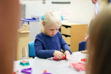 Küçük okul öncesi çocuk okulda Clay 'le oynuyor.