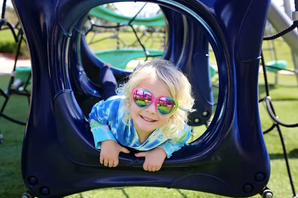 かわいい5歳の女の子がハート型のサングラスをかけて 夏の日に公園の遊び場で遊んでいるときに笑っています — ストック写真