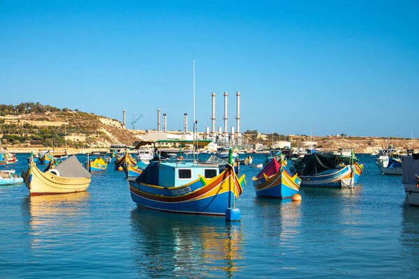 Traditional colorful Maltese fishing boat "Luzzu" in Marsaxlokk village. Boats in the blue sea, sunny day, blue sky. Malta country
