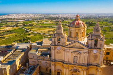 Mdina 'nın ana kilisesi - Malta' nın eski başkenti. Havadan doğa manzarası, güneşli bir gün, mavi sinsi kış, arka planda bir sürü yeşil çimen. Malta 