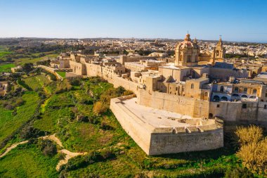 Mdina 'nın ana kilisesi - Malta' nın eski başkenti. Havadan doğa manzarası, güneşli bir gün, mavi sinsi kış, arka planda bir sürü yeşil çimen. Malta adası