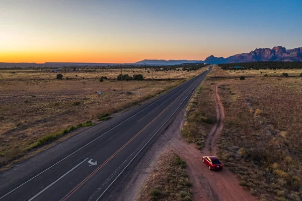 Colorado 'ya yakın bir yerde, otoyolun ve kırmızı arabanın havadan görüntüsü. Cottonwood noktası. Gün batımı gökyüzü, dağlar. Arizona, Usa