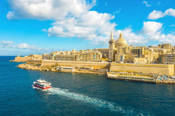 Aerial view of panorama Valletta city - capital of Malta island. Tourist red boat in Mediterranean sea. Blue sky