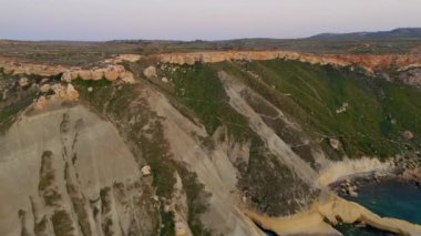 Doğa manzarasının havadan görünüşü. Akdeniz, Ghajn Tuffieha sahilindeki tepe. Kamera ileri ve yukarı hareket ediyor. Malta adası